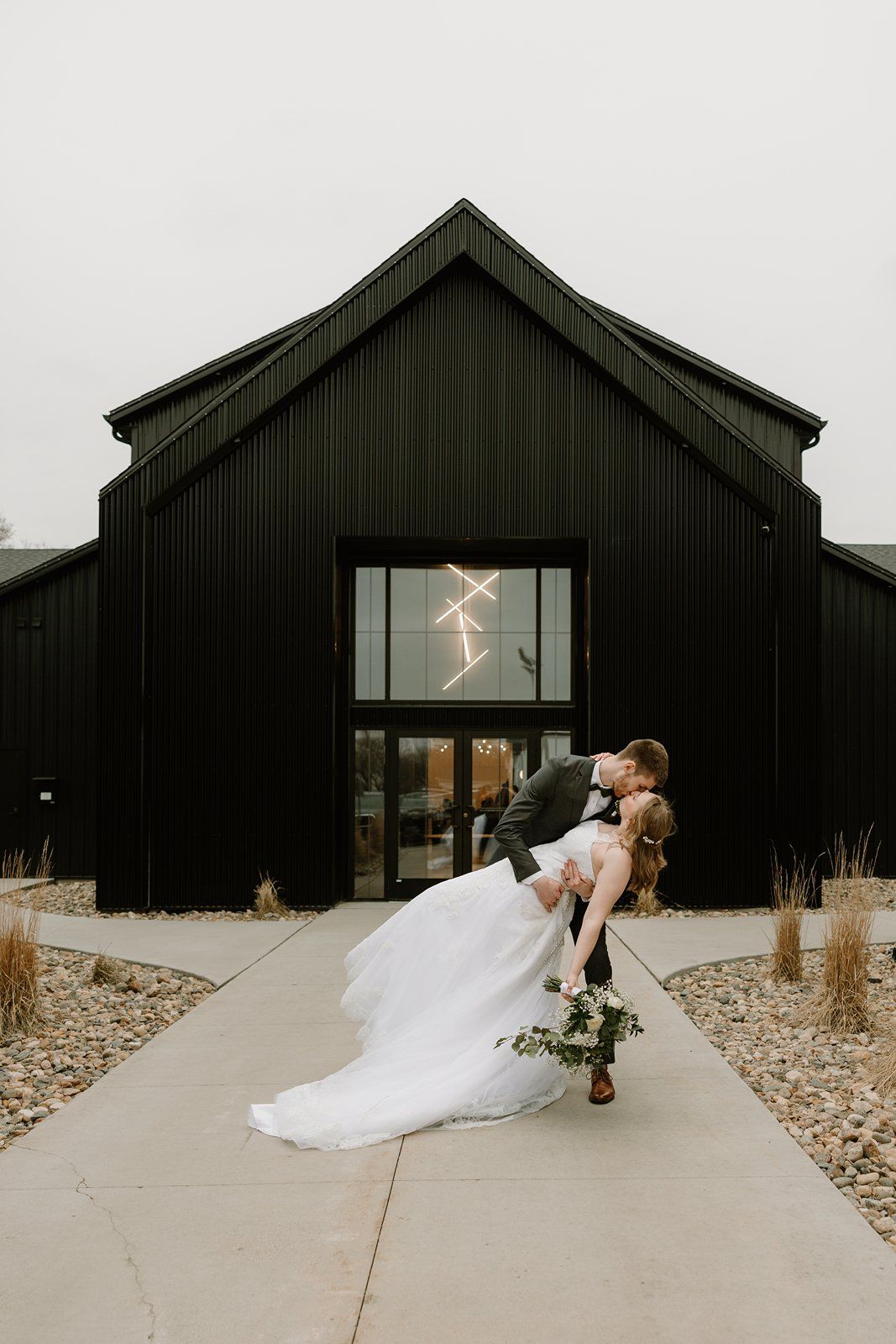A modern black barn-style wedding venue with large glass windows is shown in a series of minimalist architectural photos.