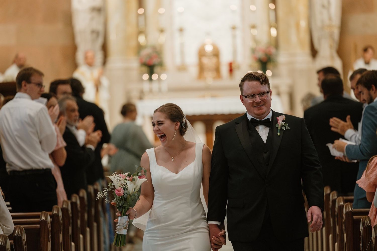 A wedding celebration inside an elegant church with guests mingling and socializing during the ceremony.