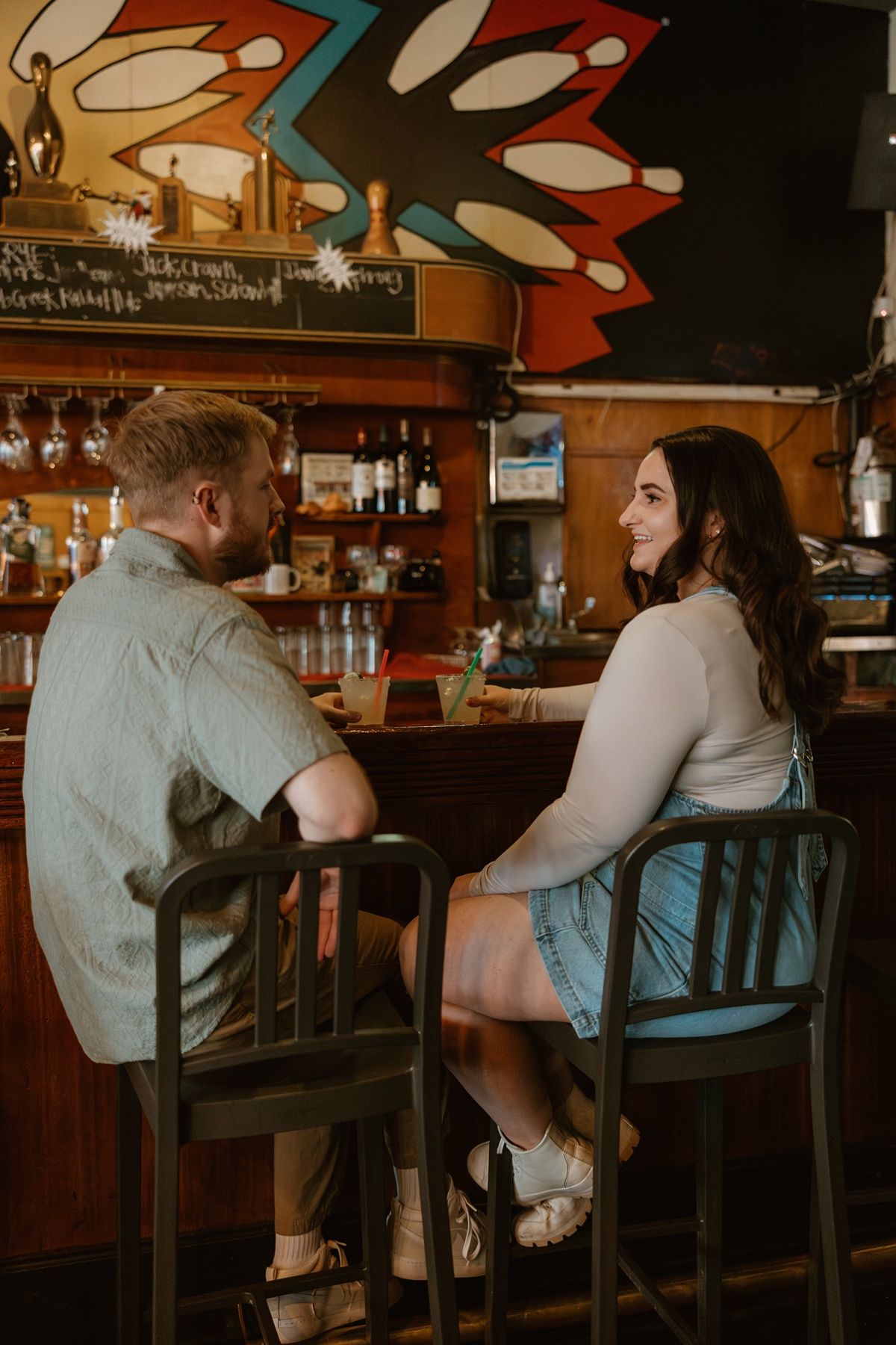 A couple sits at a wooden bar in a cozy restaurant setting, shown in a series of candid moments.
