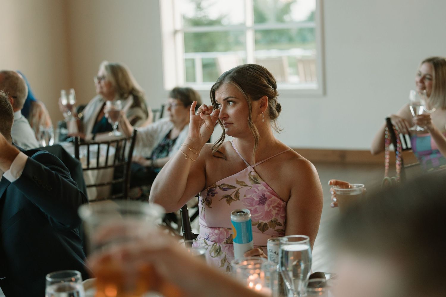 Guests seated at wedding reception tables engage in animated conversation and laughter.