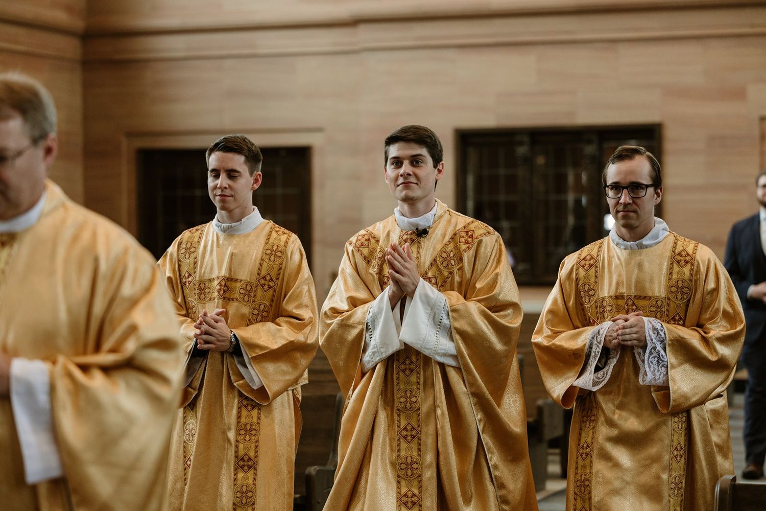 Priests in gold vestments standing in formation during a religious ceremony.