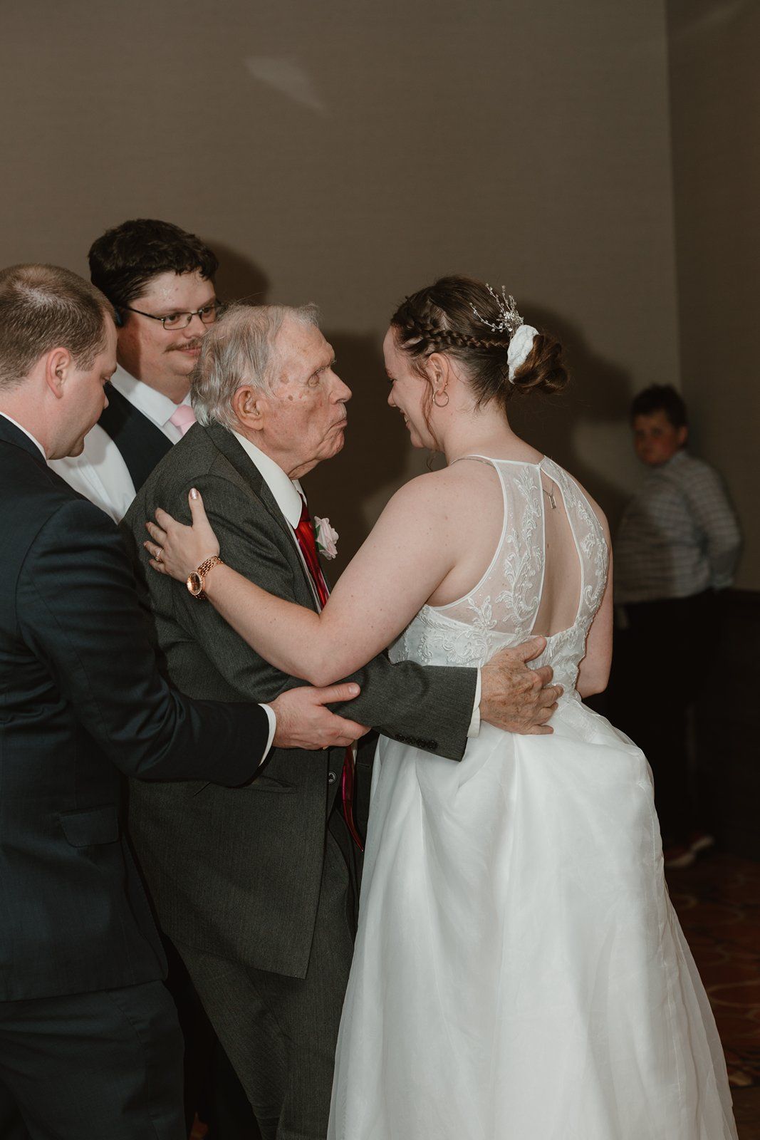 Couples dancing together during a formal wedding reception in a dimly lit ballroom.