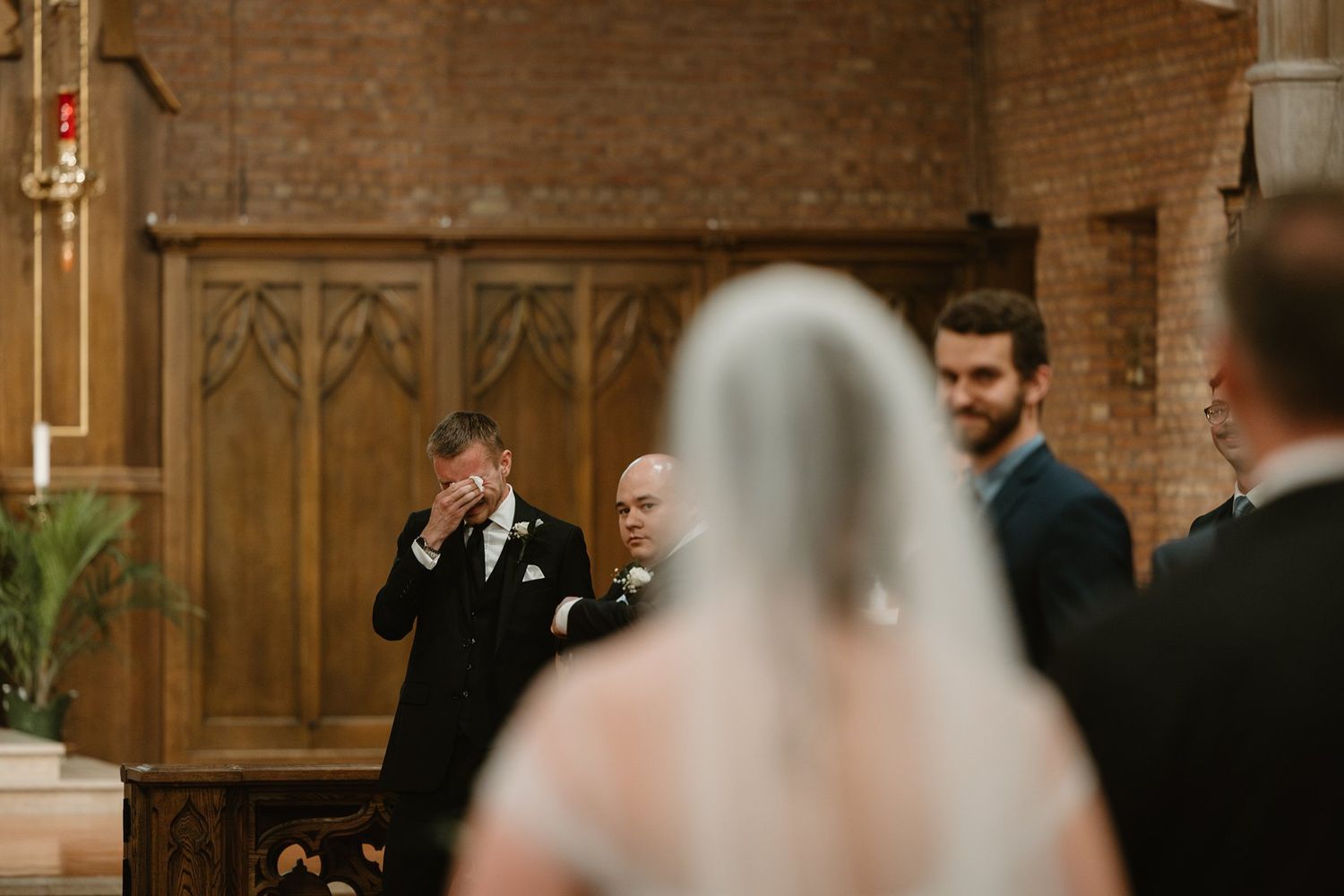 An emotional moment during a wedding ceremony inside a traditional brick church with gothic architectural details.