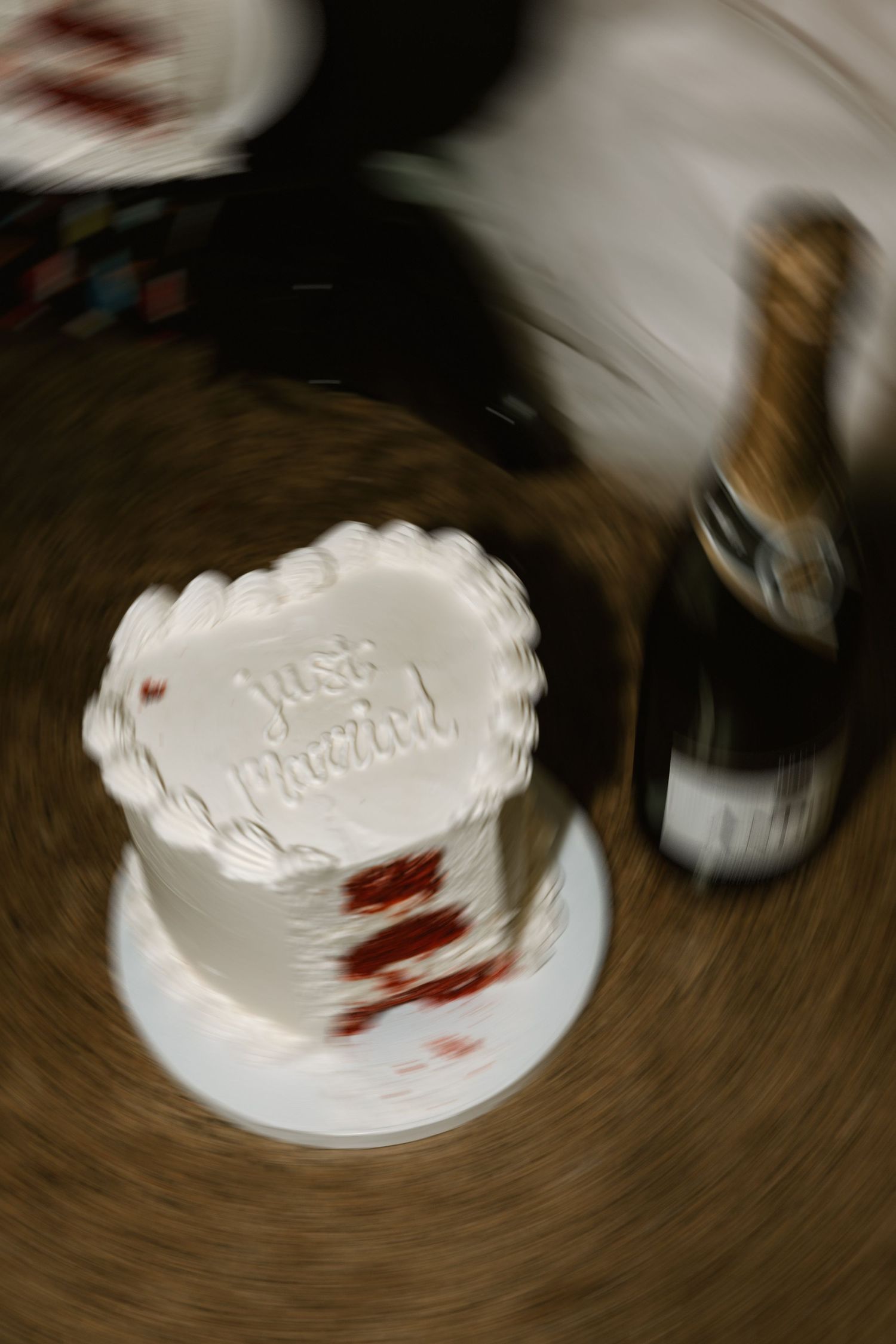 A blurry wedding cake with 'Just Married' text and a bottle of champagne in the background.