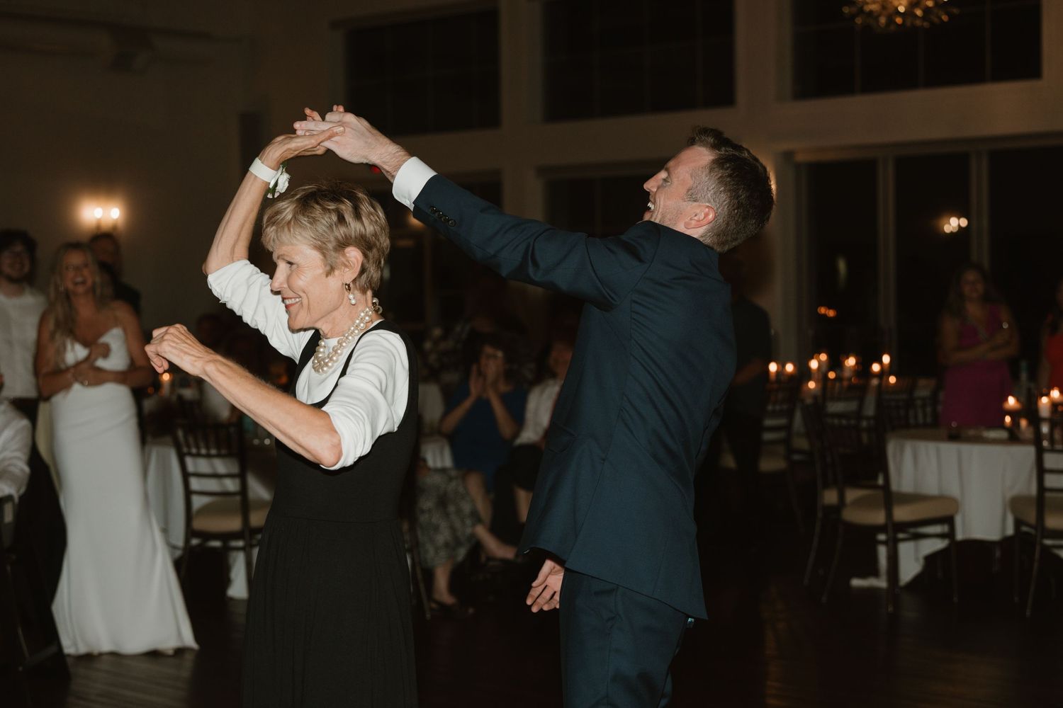 Two people dancing together at an elegant evening reception with guests watching in the background.
