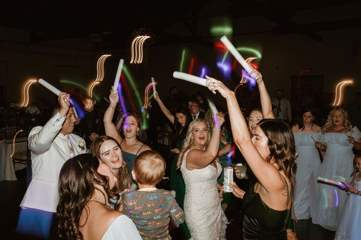 Wedding party dancing with colorful LED glow sticks creating a festive atmosphere.