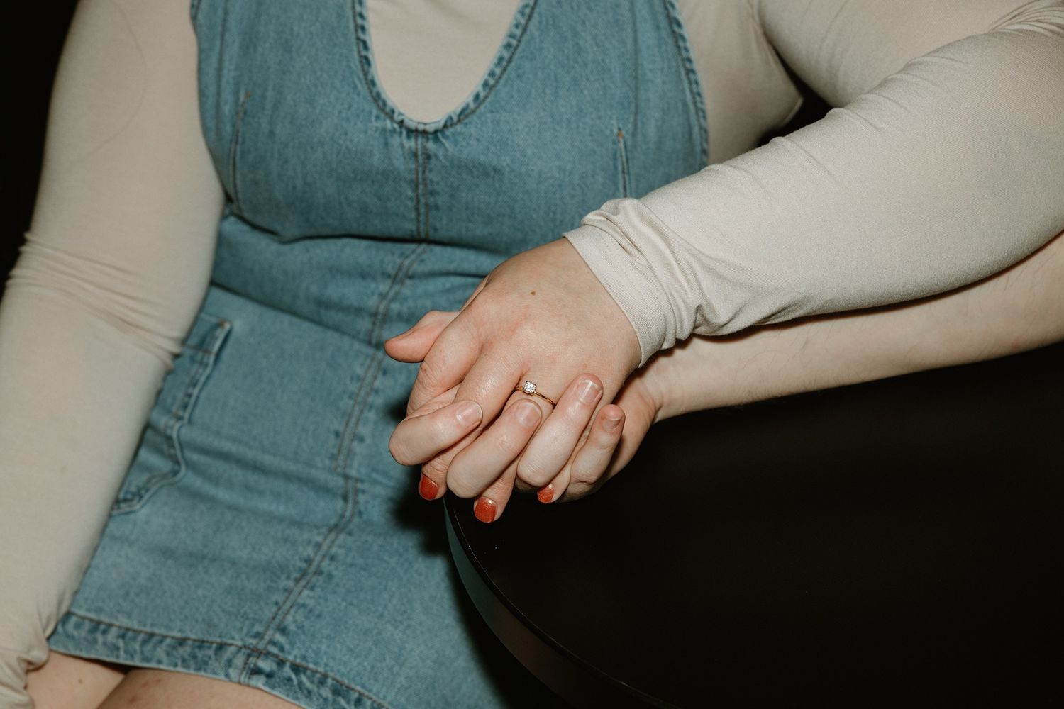 Close-up shot of hands wearing denim against a neutral background.