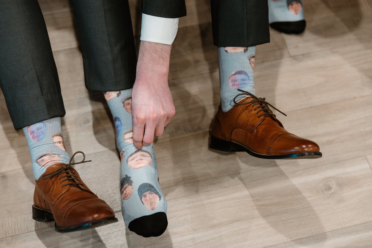 Brown suede oxford shoes paired with light blue and coral striped socks shown from different angles on wooden floor.