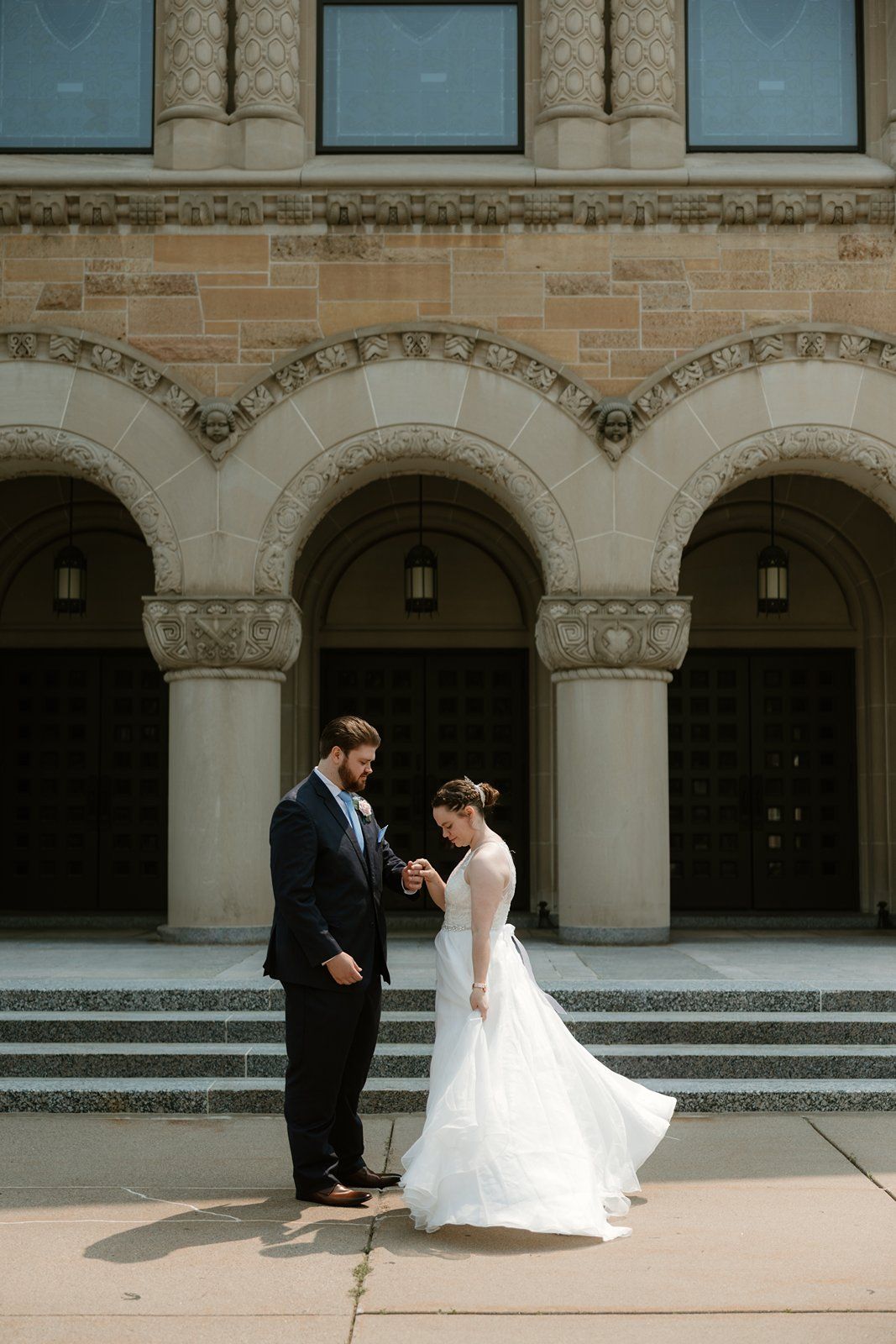 A bride and groom share a romantic moment in a stone archway courtyard of a historic building.
