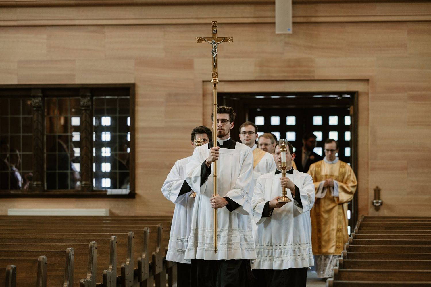 Church choir members in white robes stand together during a religious service in a traditional wooden sanctuary.
