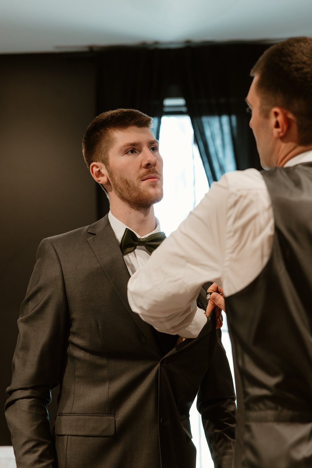 A sequence of images showing someone adjusting a bowtie on a person wearing a dark suit.