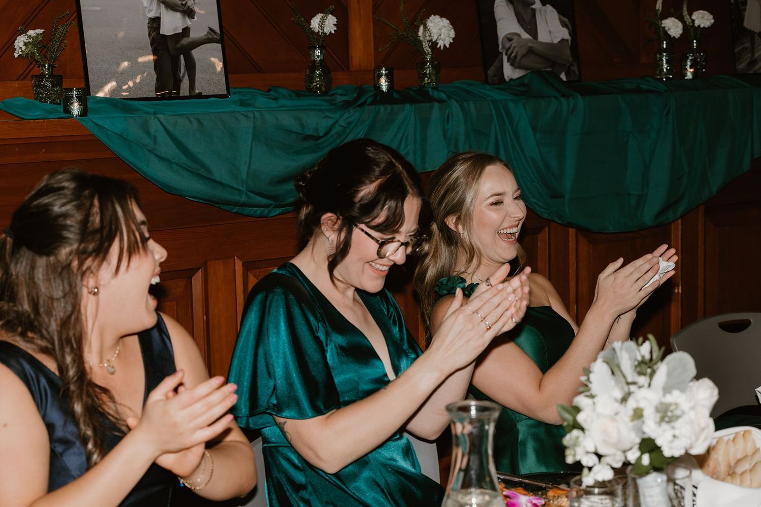 Wedding guests in teal attire react enthusiastically during a reception celebration.