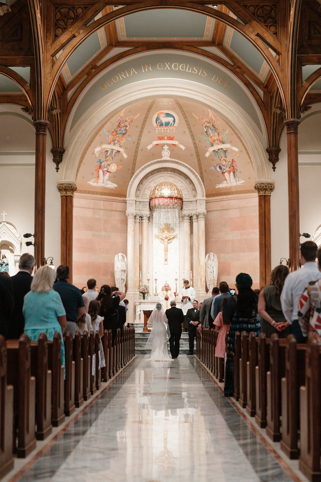Interior view of a grand Catholic church with ornate arched ceiling and rows of wooden pews.