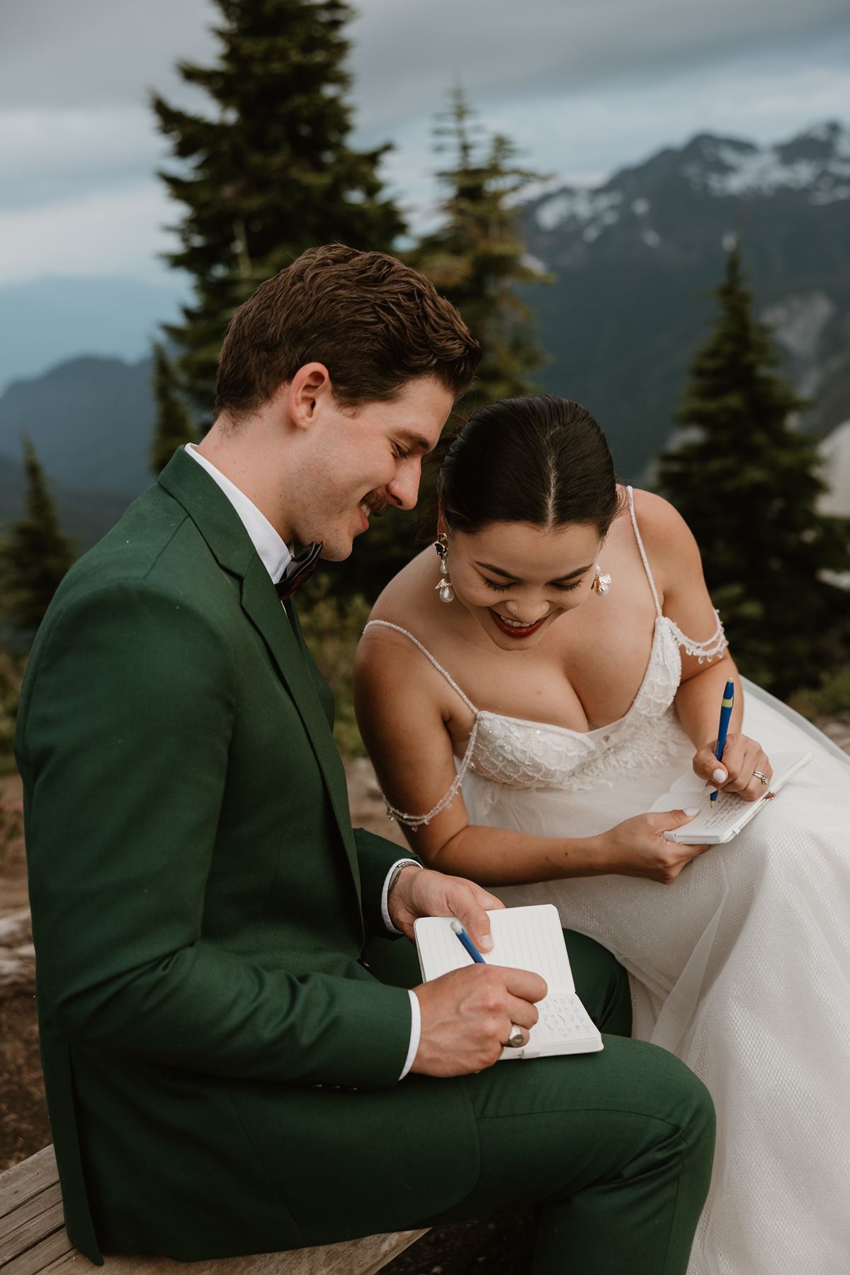 adventure elopement photographer captures couple writing vows in the mountains before their ceremony