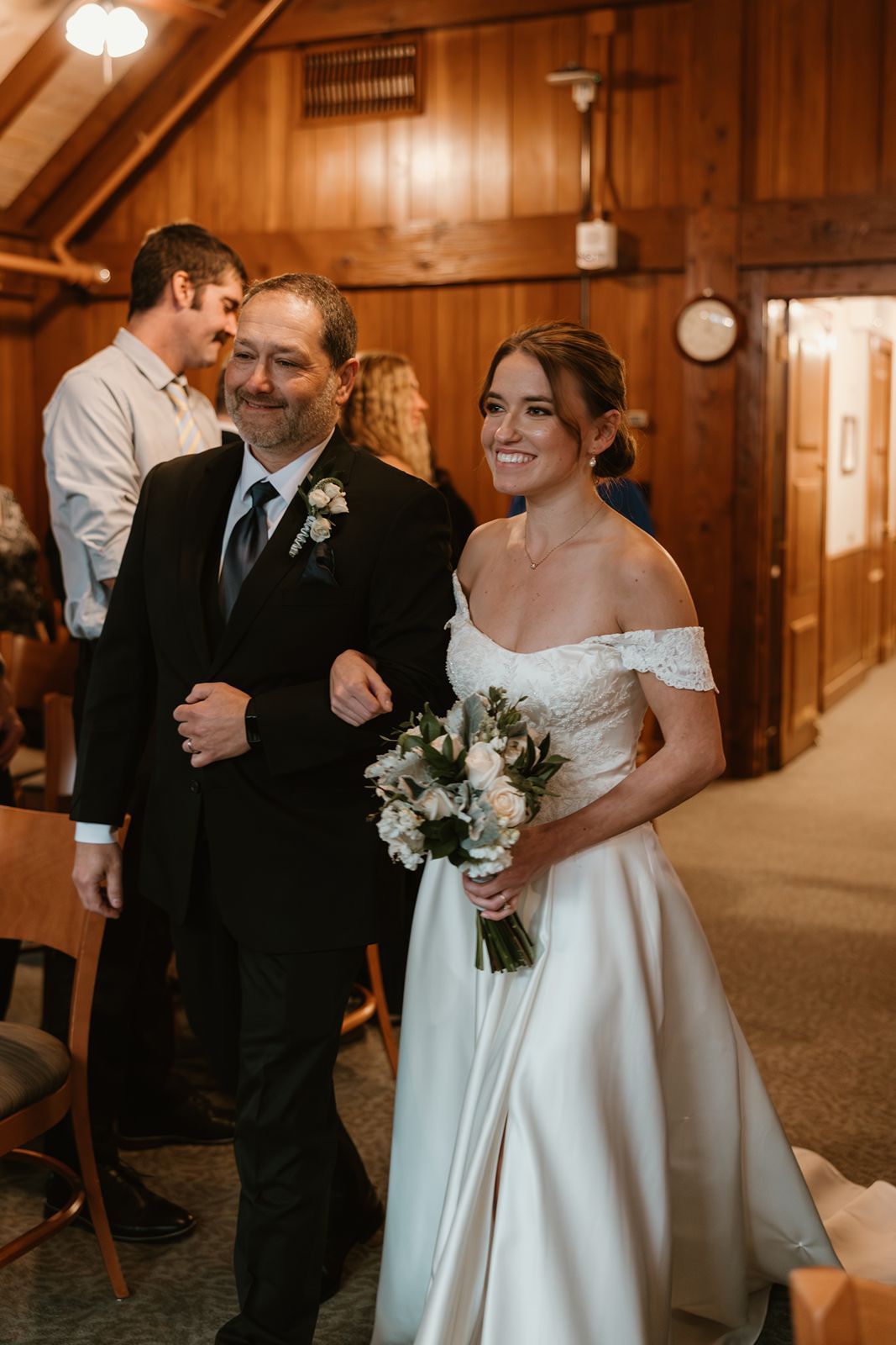 bride and her father walk down the aisle at her wedding ceremony in the Fireplace Room at the MN arboretum.
