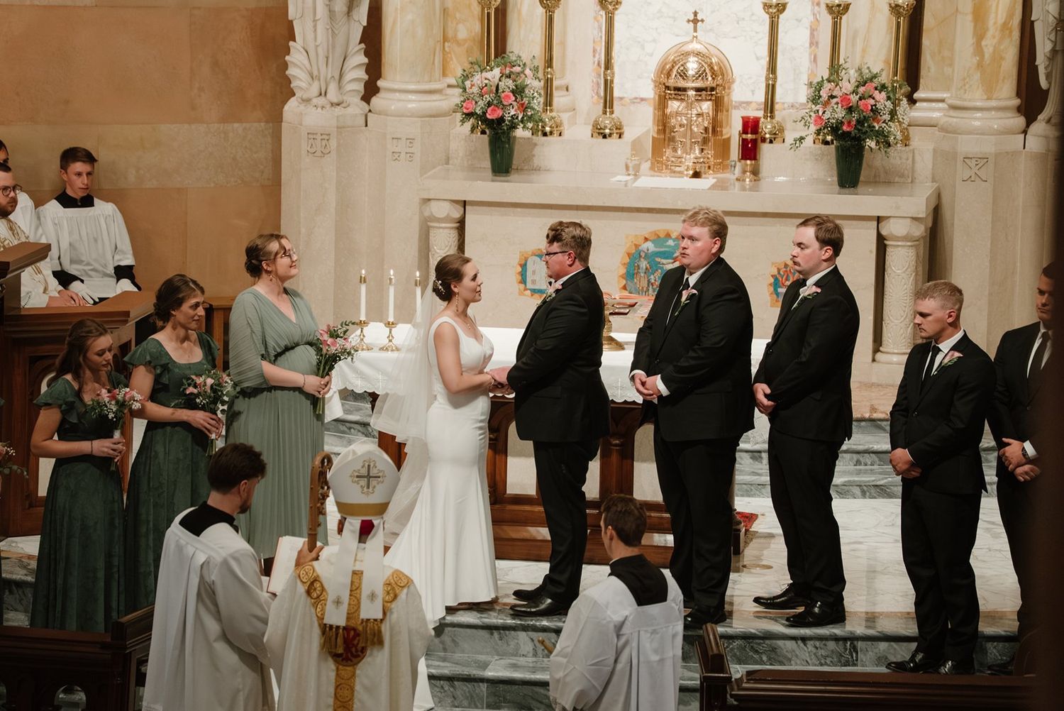 Traditional Catholic church wedding ceremony with guests and wedding party at the altar.