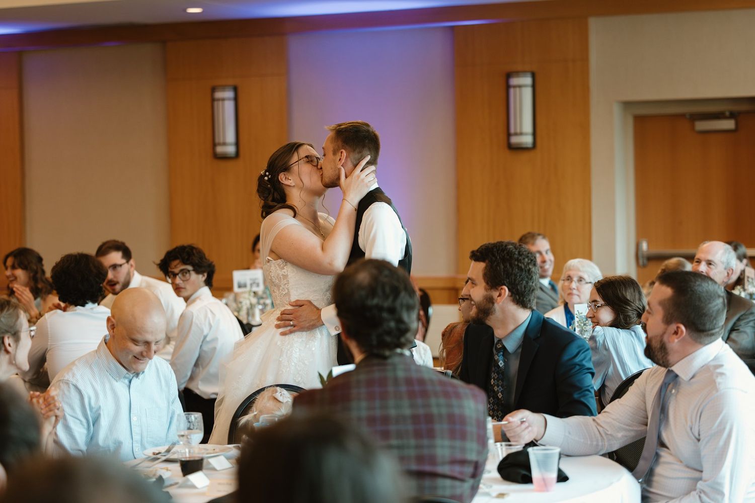 A couple shares their first dance at a wedding reception while guests watch from their tables in a banquet hall.