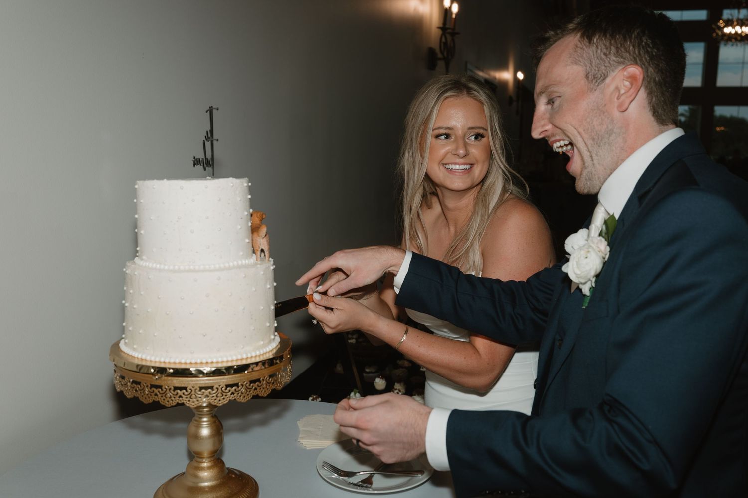 A couple cuts into their white wedding cake during their reception celebration.