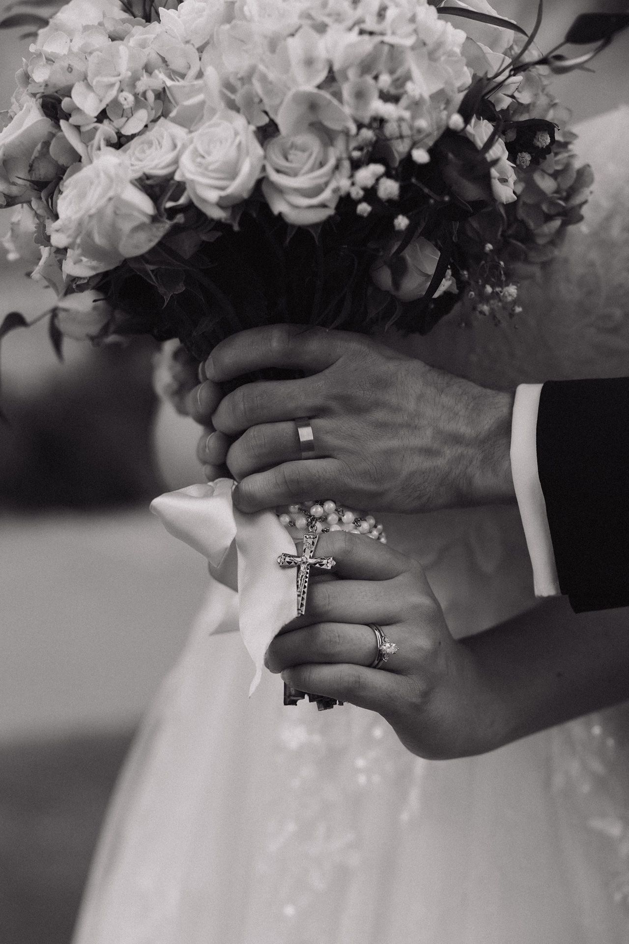 couple holding rosary around bridal bouquet taken by a Catholic wedding photographer