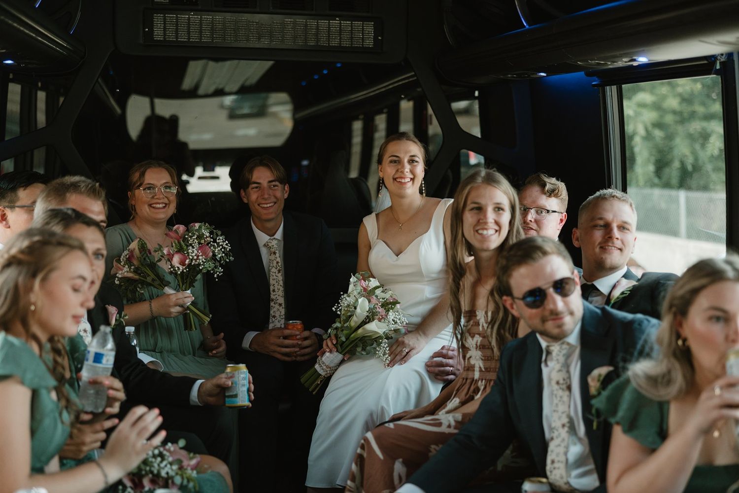 Wedding guests celebrate and laugh together while riding in a party bus during a festive celebration.