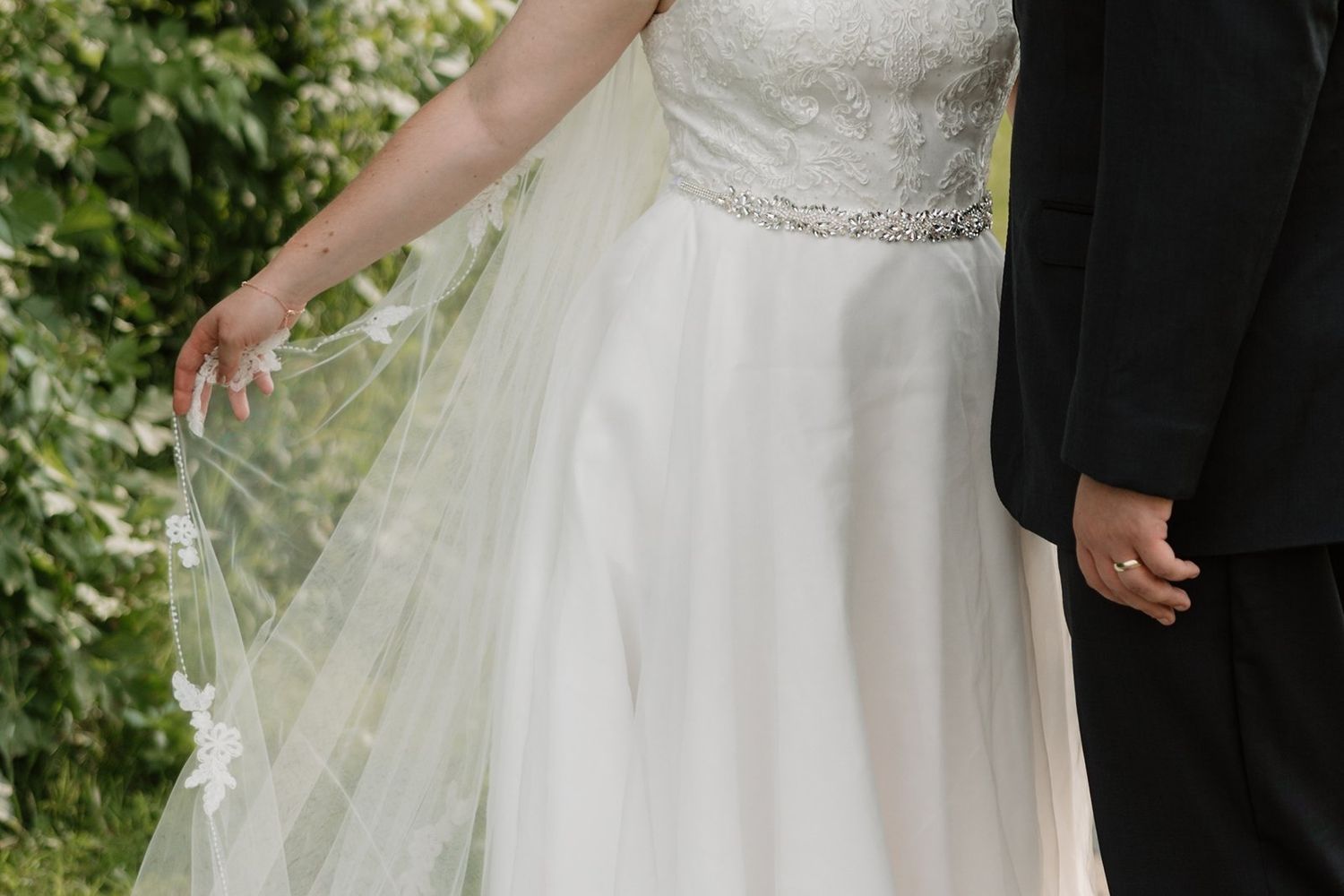 A close-up detail shot of a white beaded wedding dress bodice with intricate embellishments and lace detailing.