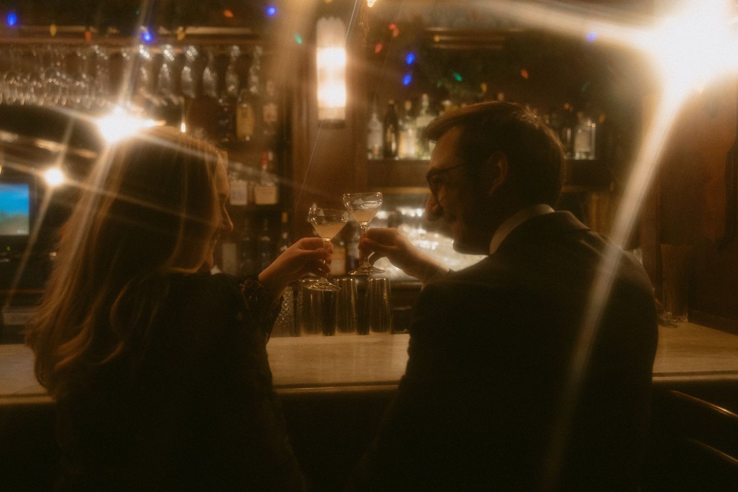 A blurry sepia-toned view of a vintage bar counter with silhouettes in soft focus.