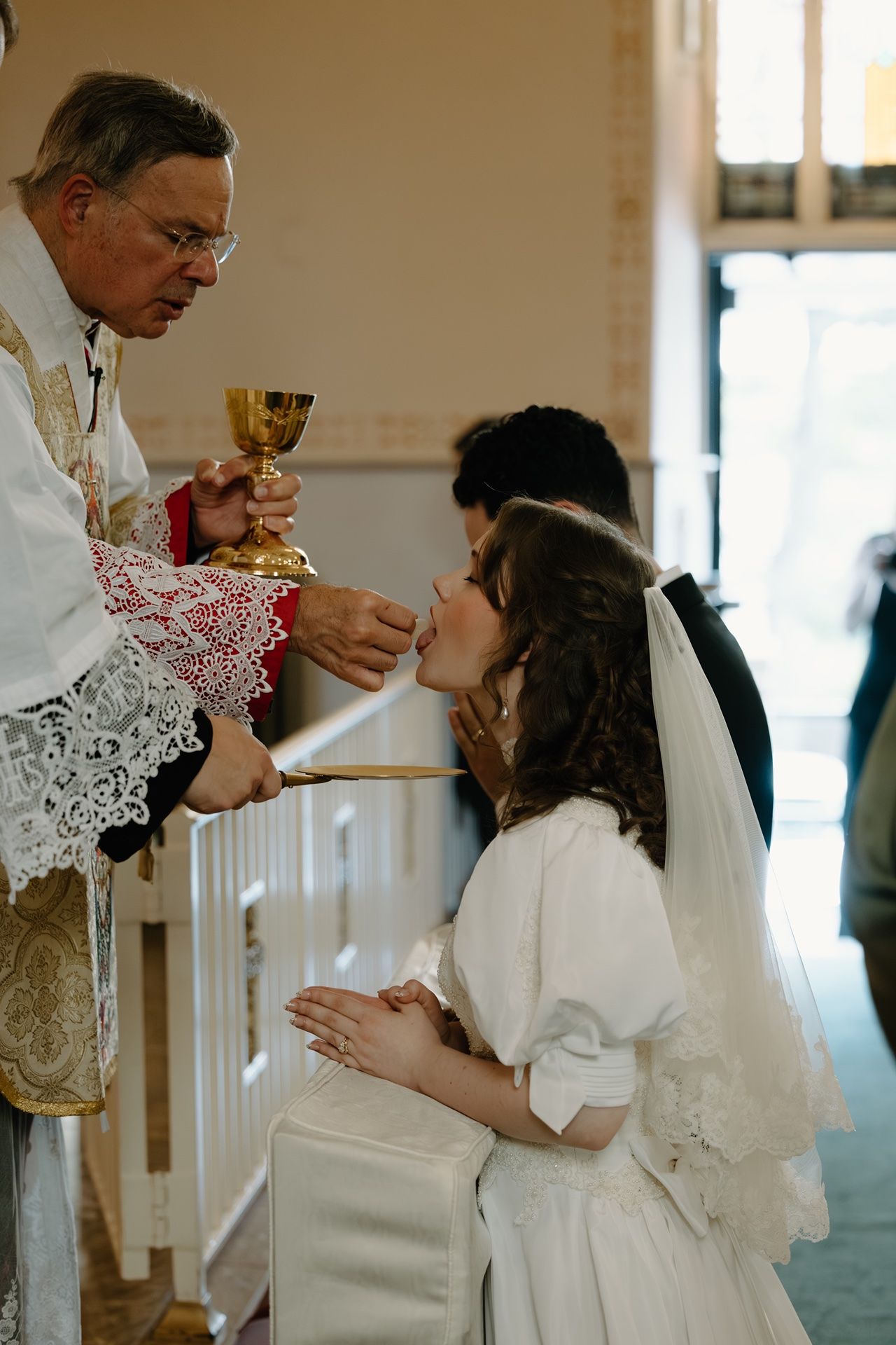 Bride receiving communion during a traditional latin mass wedding captured by a Catholic photographer