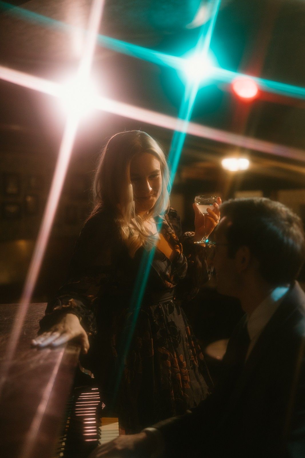 A dreamy nighttime photo with lens flares showing silhouettes in moody lighting with teal and white starbursts.