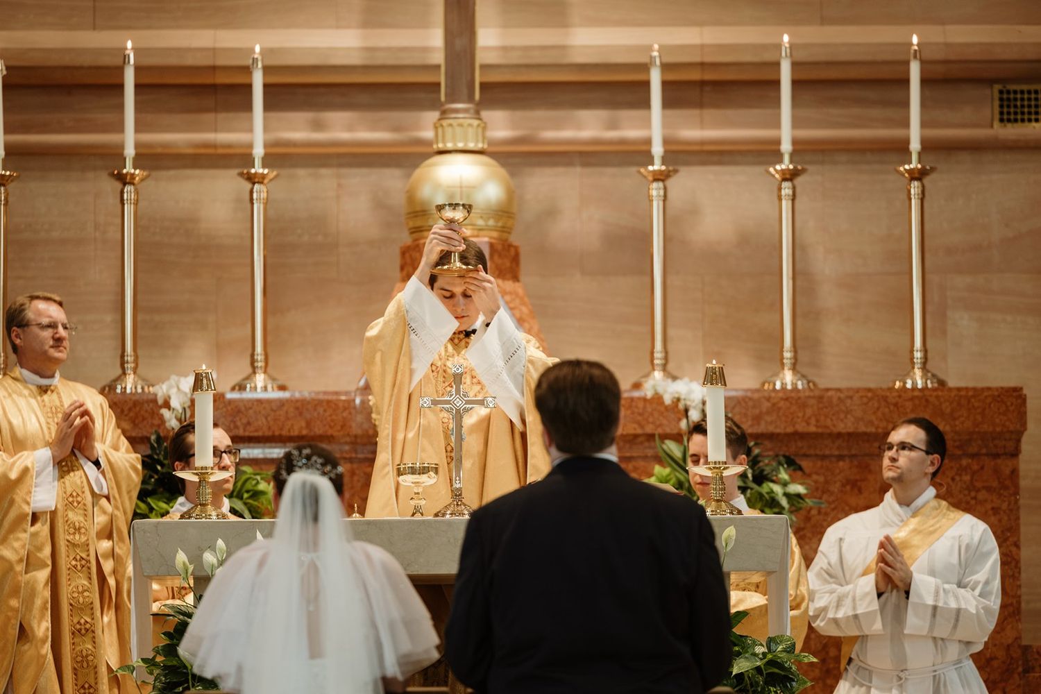 Church altar decorated with candles and clergy during a ceremony.