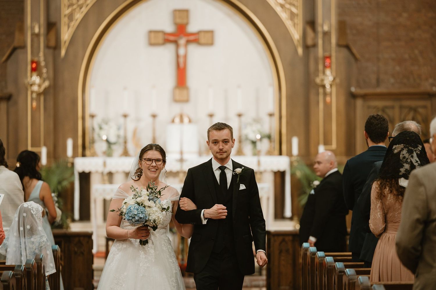 A wedding ceremony takes place in a traditional church with ornate architecture and religious symbols.