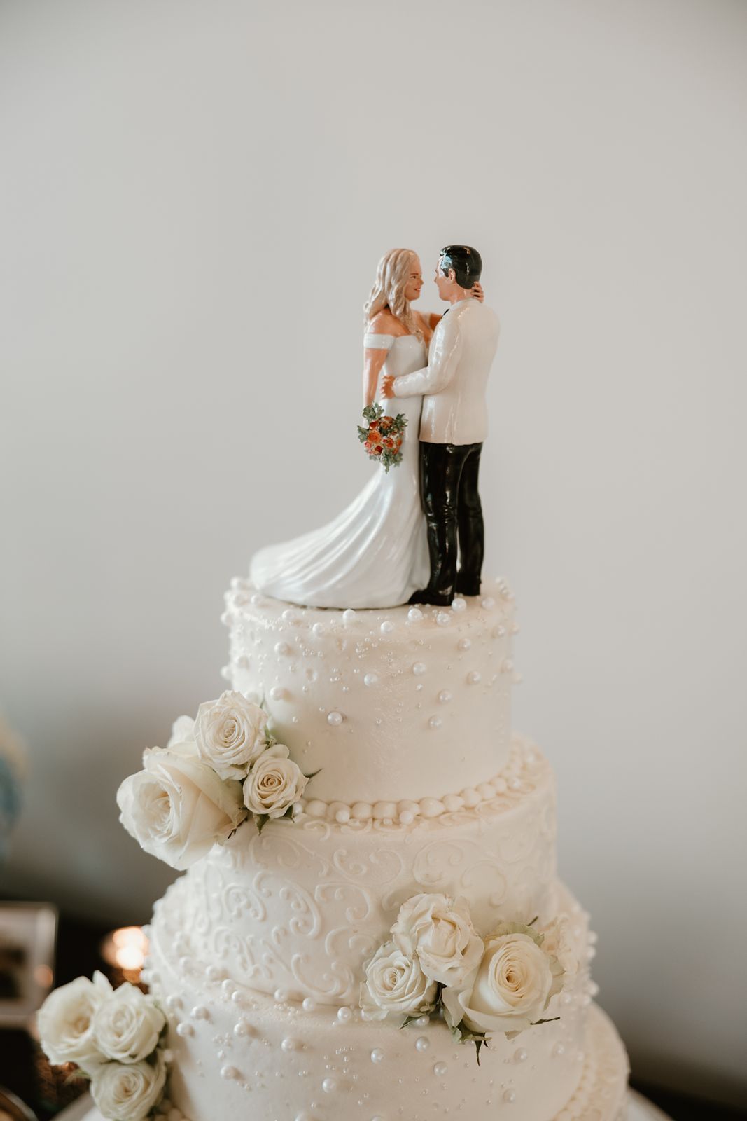 Elegant white wedding cake topped with a traditional bride and groom figurine.