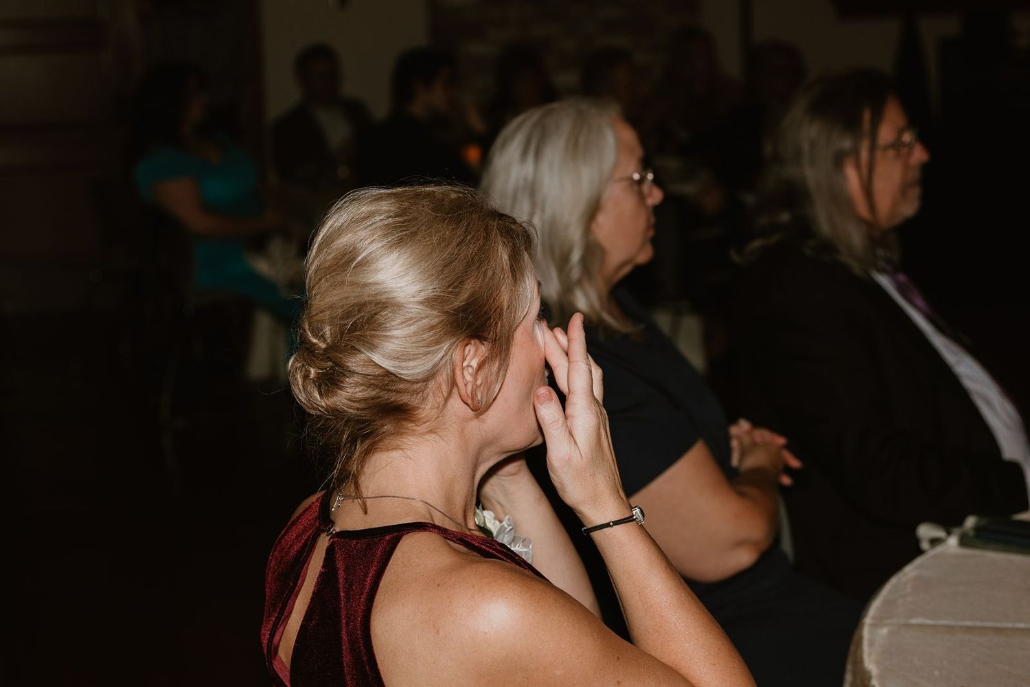 Wedding guests show emotional reactions during a special moment at the reception.