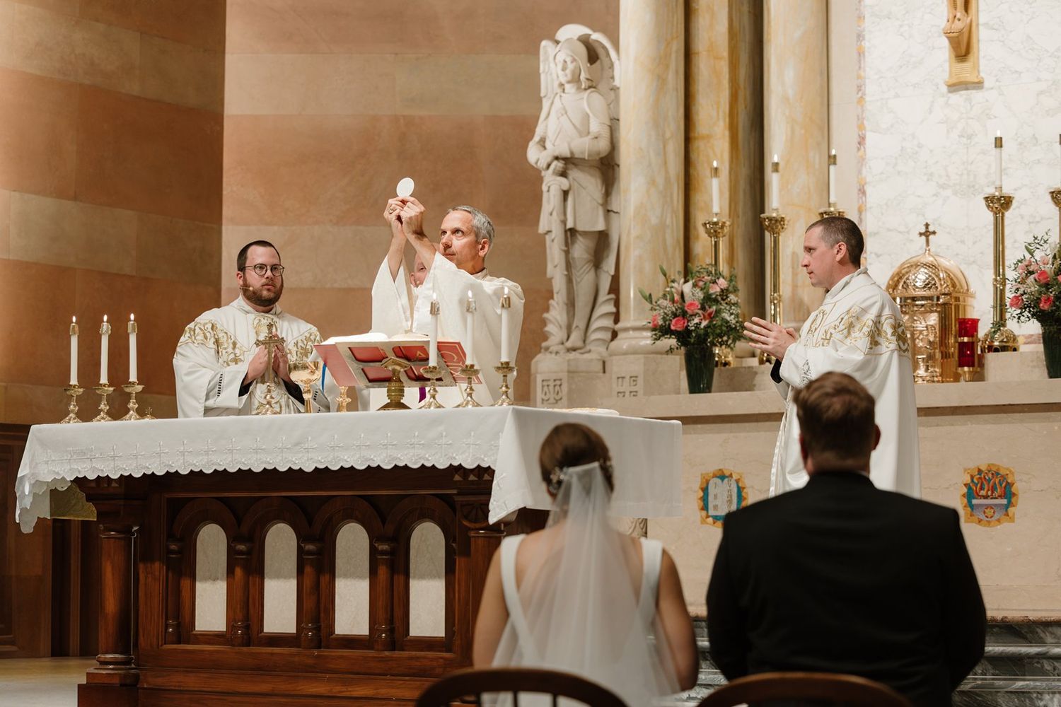 Traditional Catholic church wedding ceremony with participants gathered at the ornate altar.