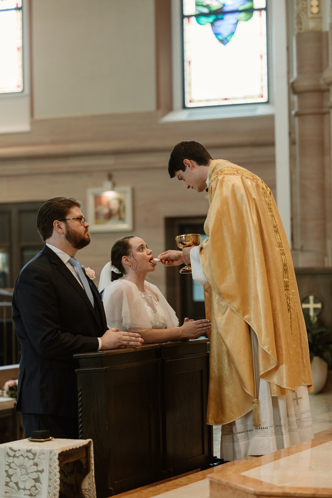 A priest administers Holy Communion to a couple during a traditional church wedding ceremony.