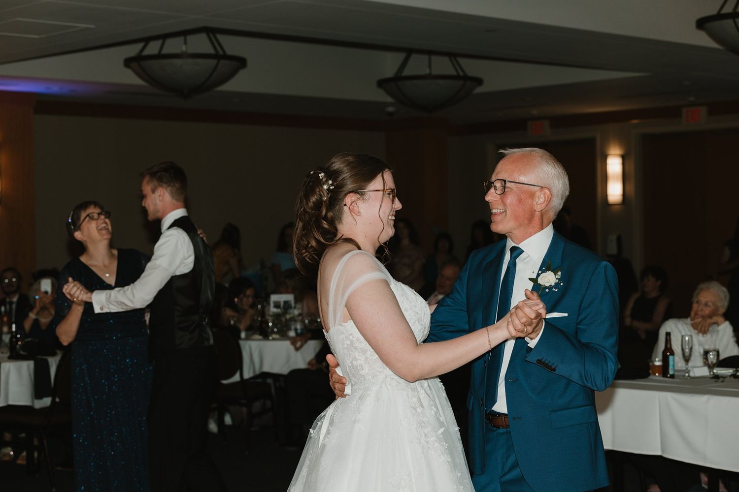 Couples dancing together at a wedding reception in a dimly lit venue.