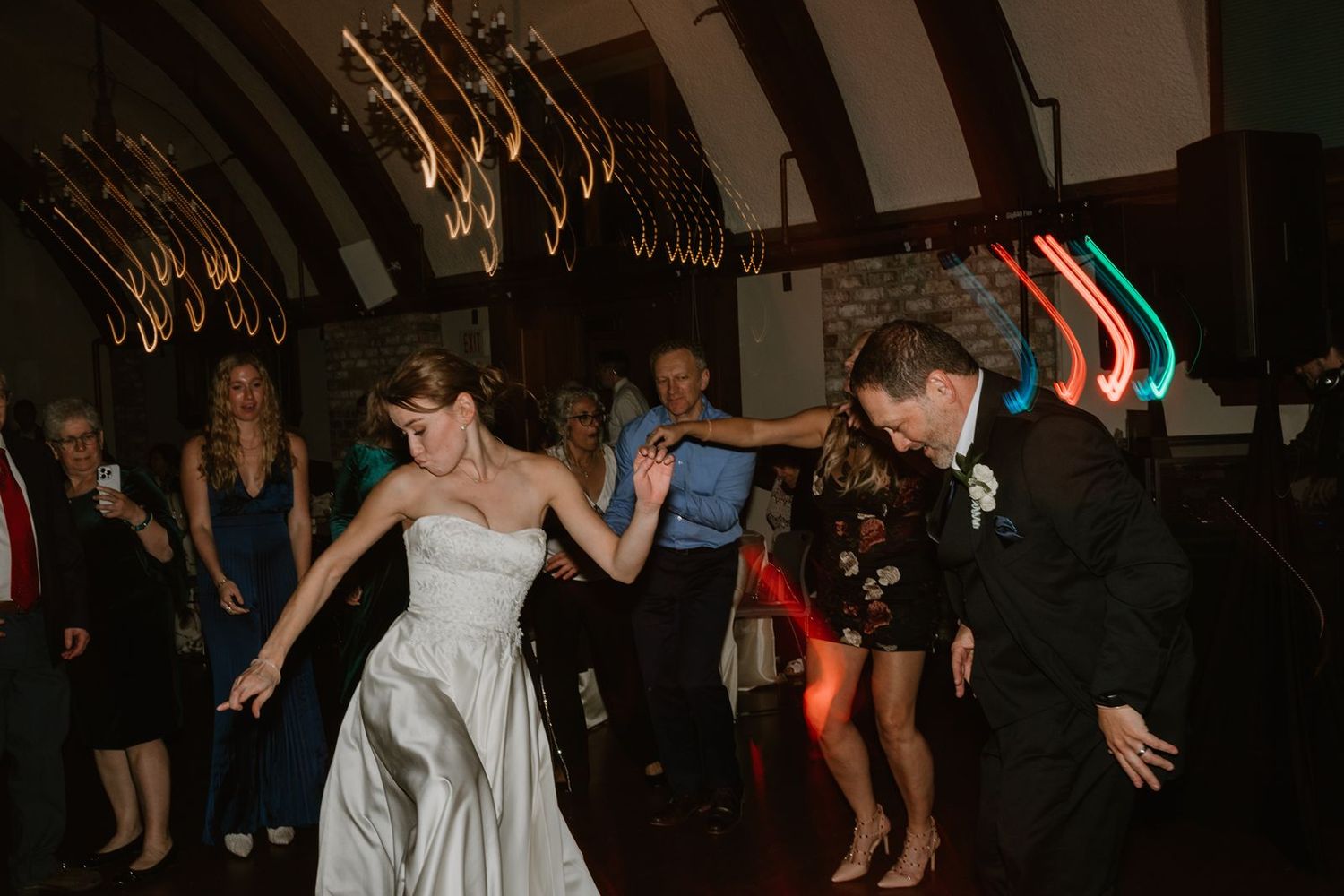 Celebration on the dance floor with guests dancing under decorative lighting.