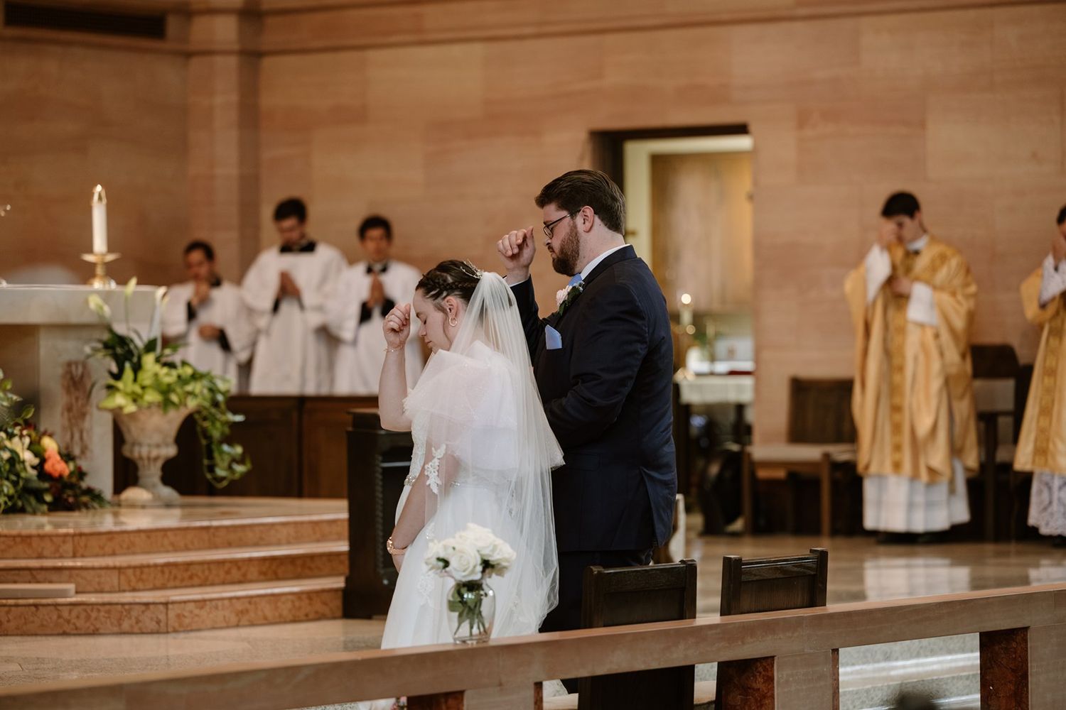 Wedding ceremony taking place in a grand church sanctuary with stone walls and altar candles.