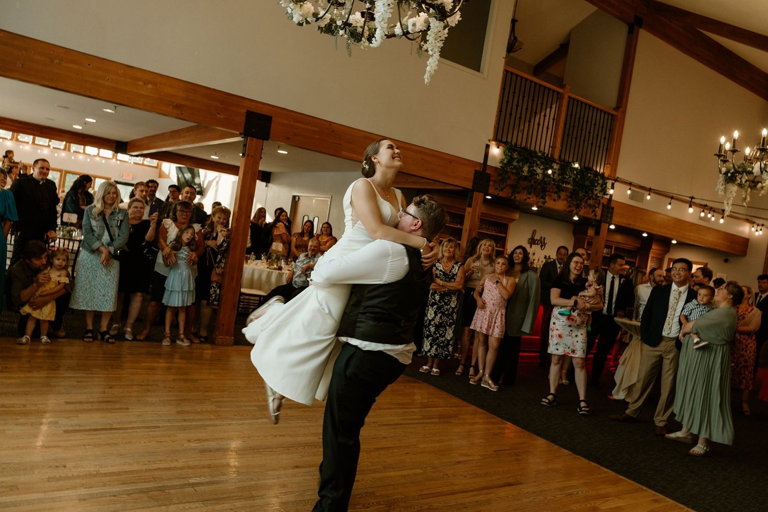 A couple performs an elegant dance move at a wedding reception as guests watch from the sides.