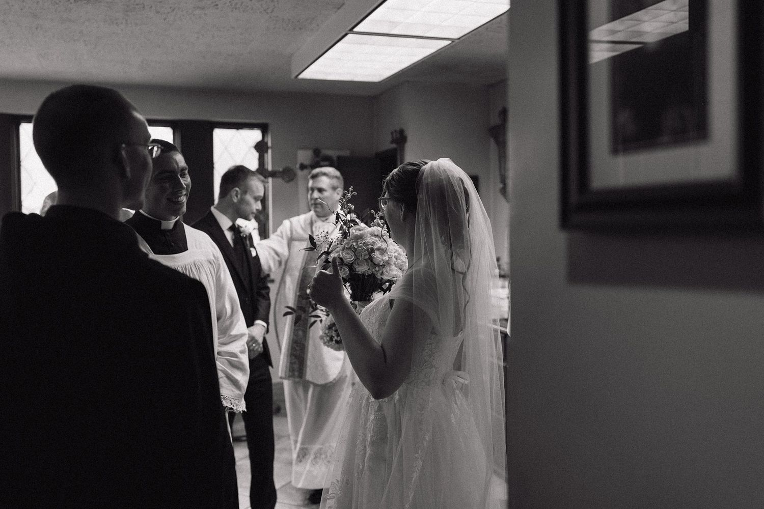 Black and white wedding photo capturing a candid moment during the ceremony with guests looking on.