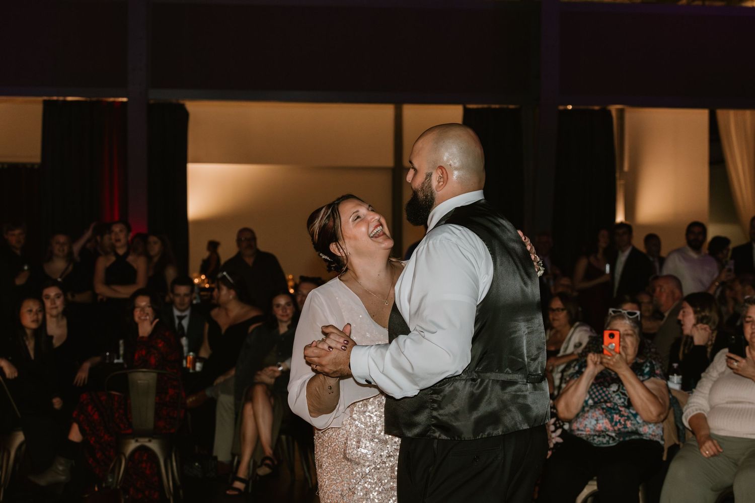 A couple shares a special moment during their first dance at a wedding reception with guests watching in the background.