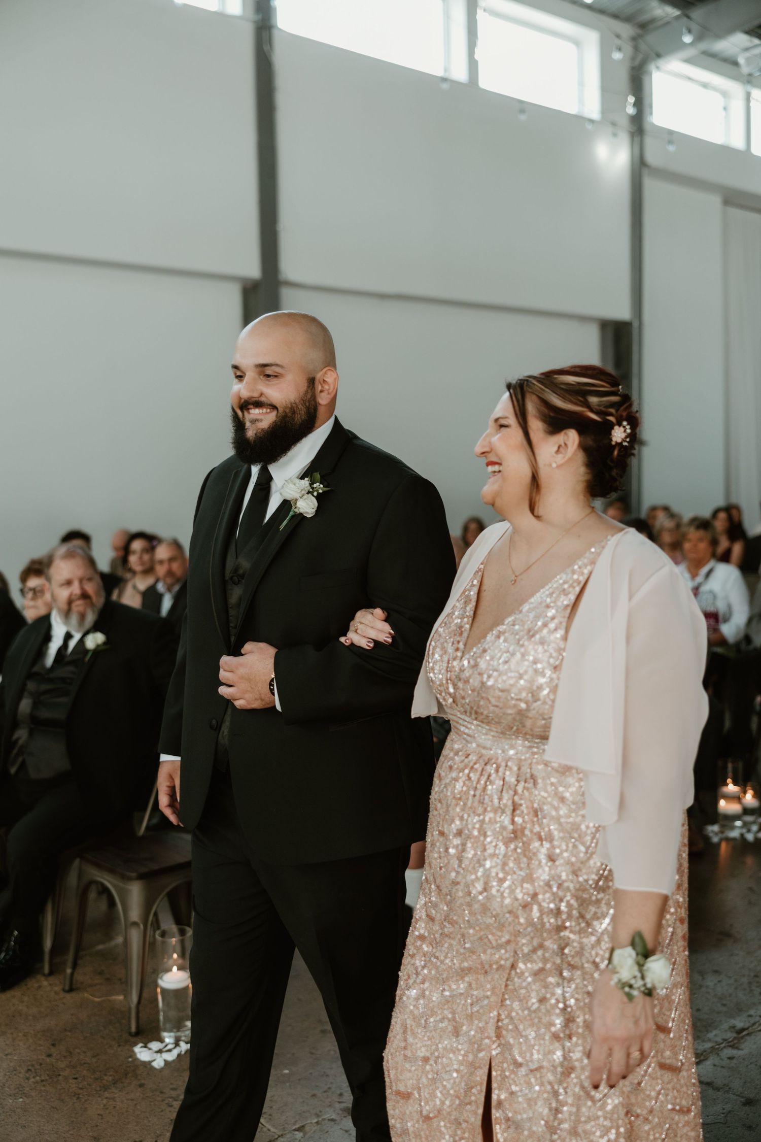 A wedding couple shares a joyful moment during their ceremony in a modern industrial-style venue.