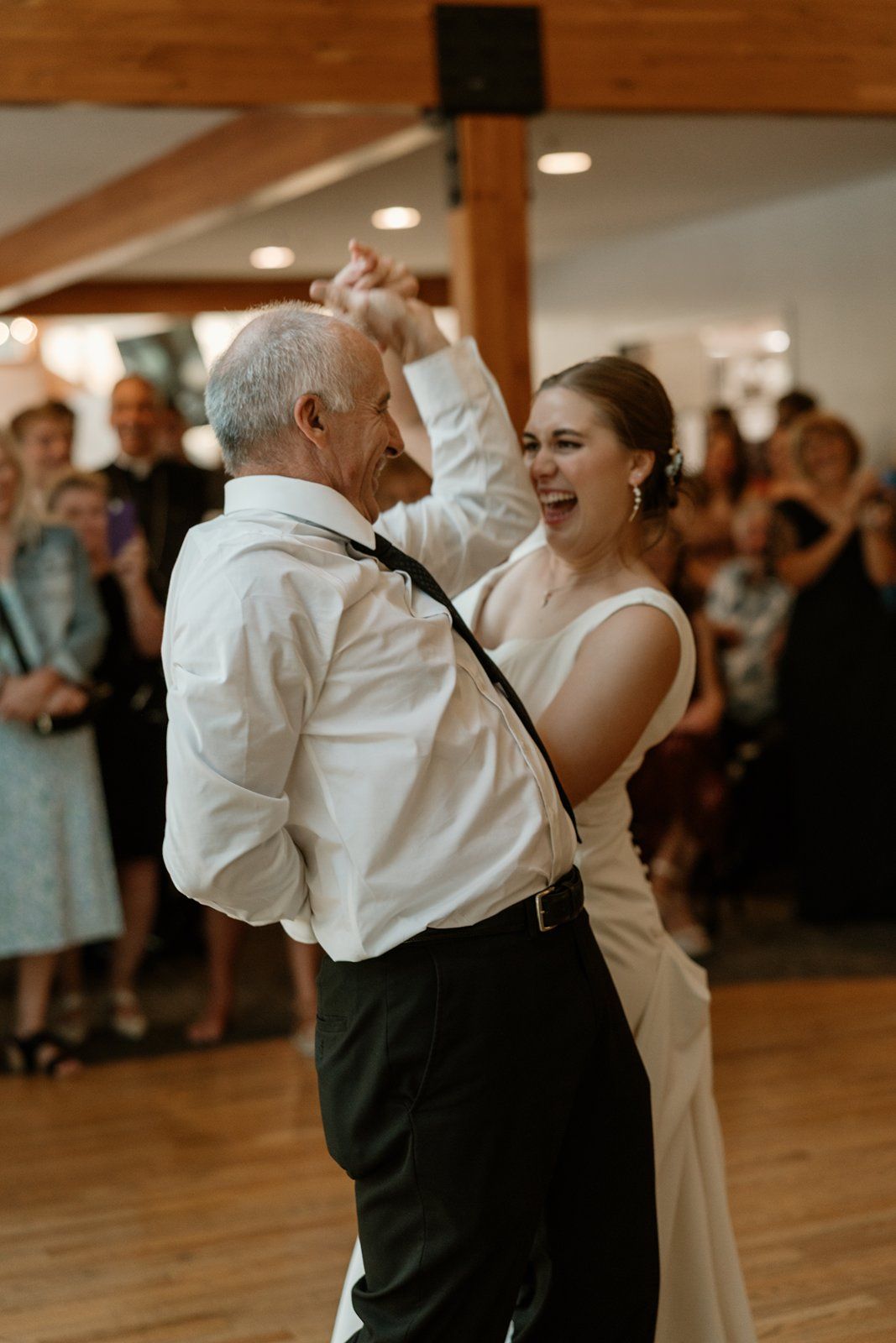 A joyful dance moment captured between two dancers in formal attire on a polished wooden dance floor.