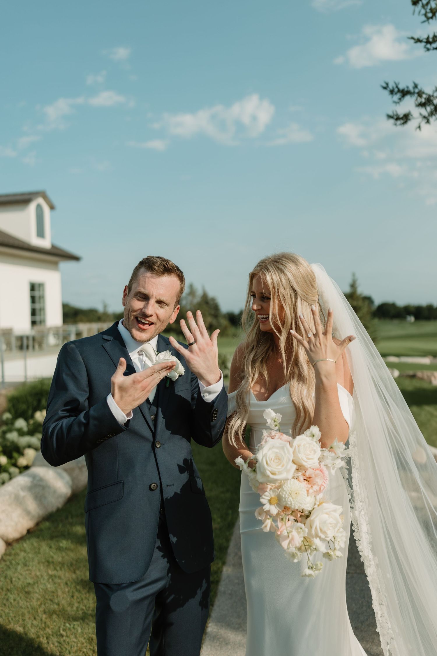 A candid moment of newlyweds laughing together on their wedding day against a scenic outdoor backdrop.
