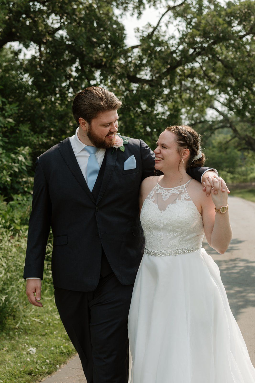 A couple in wedding attire shares intimate moments together outdoors surrounded by lush greenery.