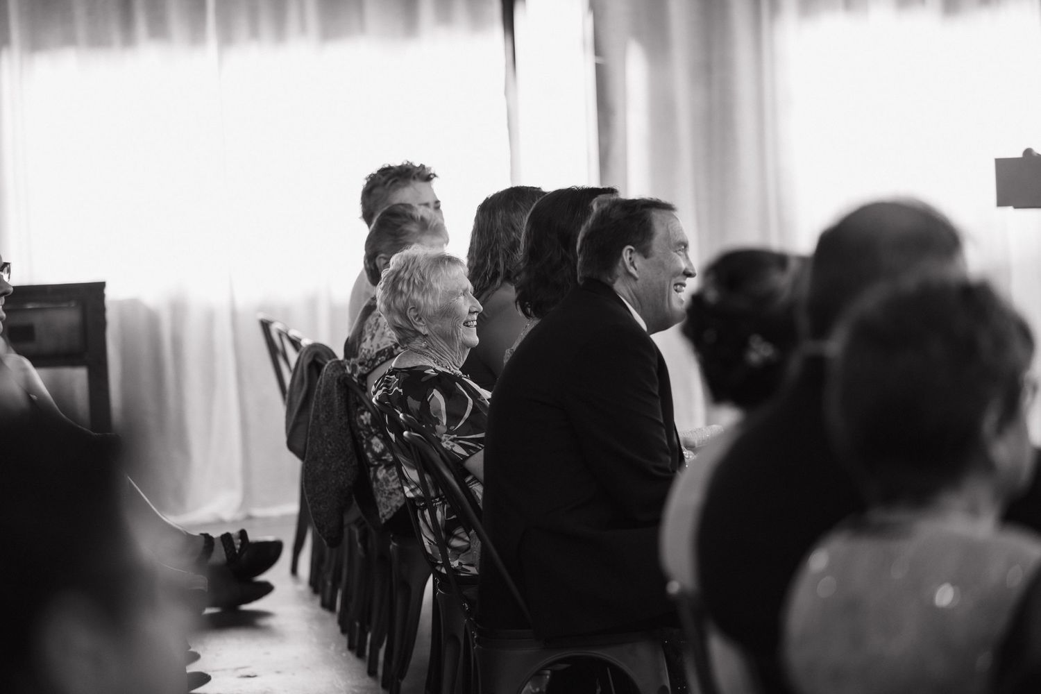 A group of people stand together during what appears to be a formal indoor gathering captured in black and white.