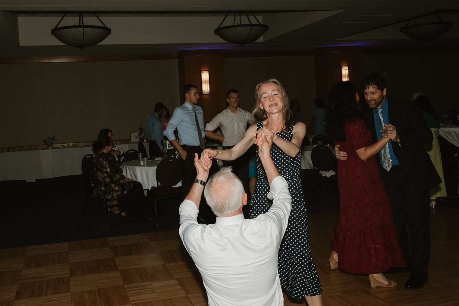 Dancers move together with one lifting the other during a formal dance event in a dimly lit venue.