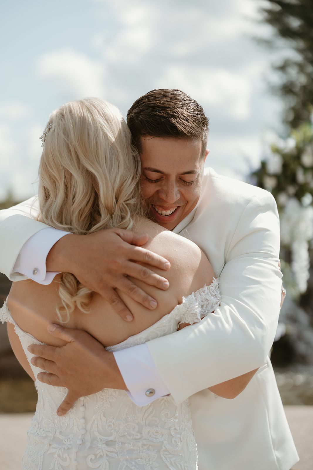 An emotional embrace between newlyweds during their outdoor wedding celebration.