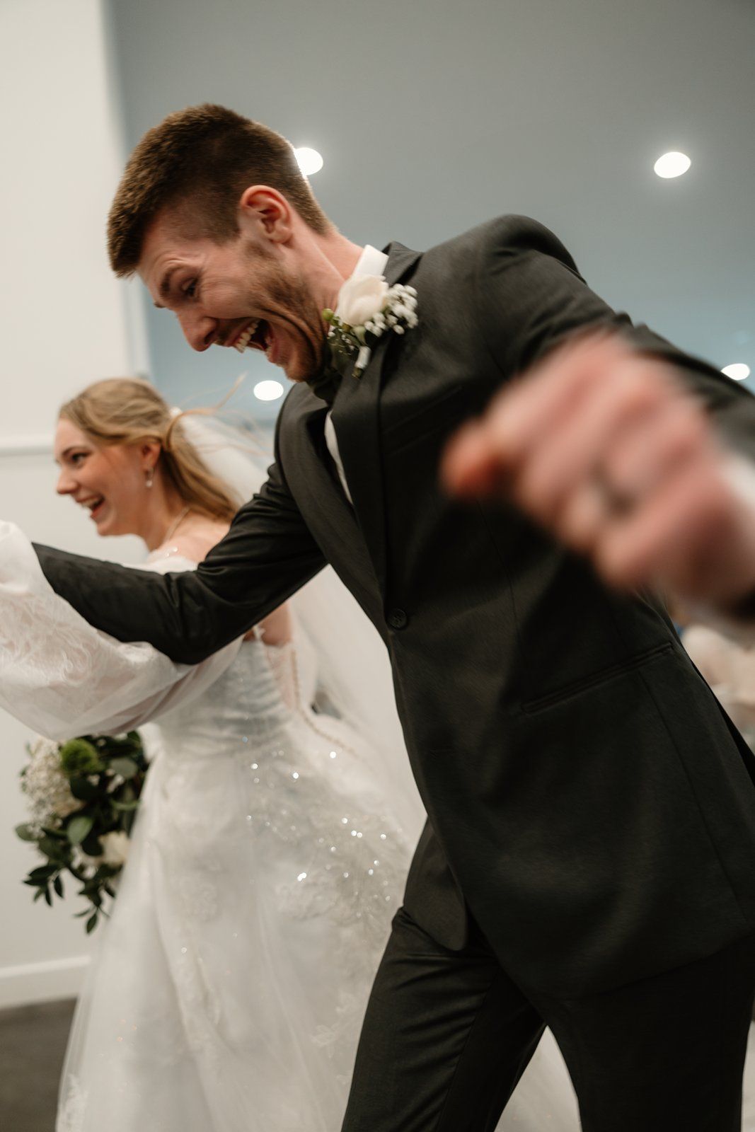 Joyful newlyweds celebrate with energetic dance moves at their wedding reception.