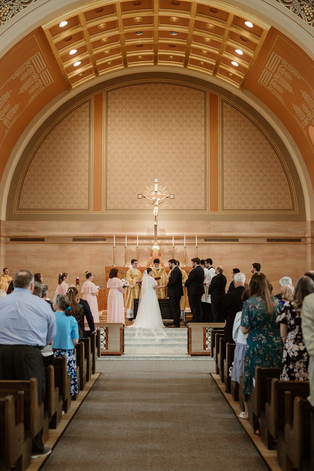 Church sanctuary with vaulted ceiling and wooden pews filled with wedding guests.