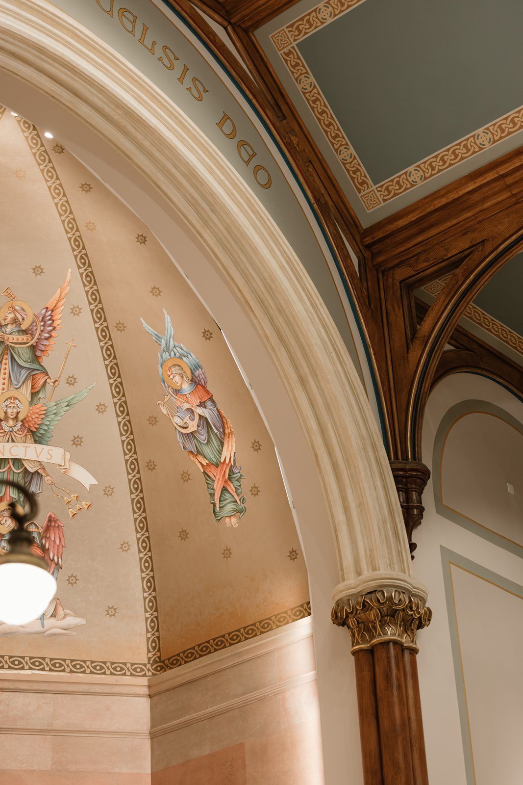 Ornate cathedral ceiling with decorative arches, columns and painted cherub figures in a classical architectural style.